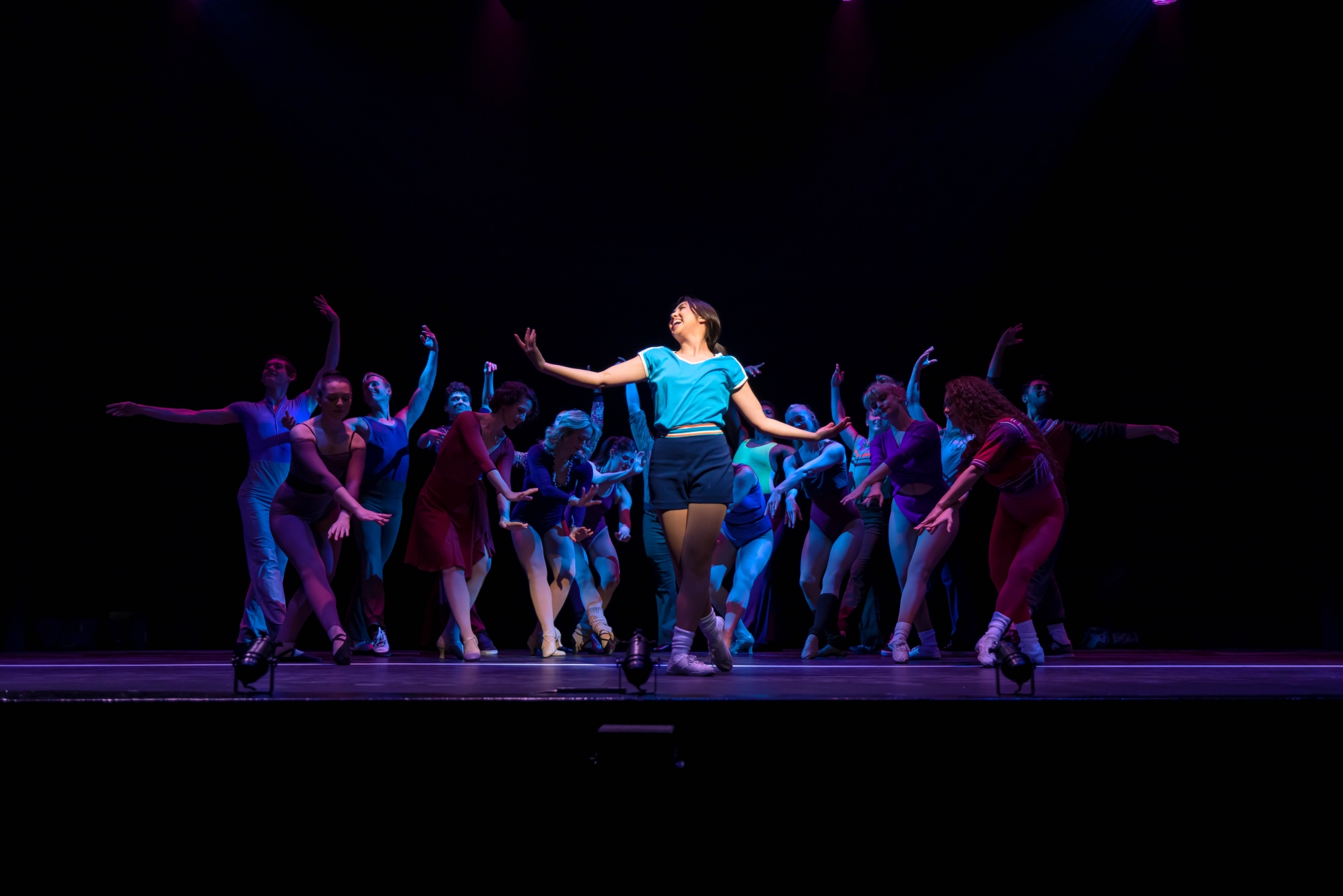 Justine Rappaport as Connie in A Chorus Line stands gracefully in front of a group of auditioners.