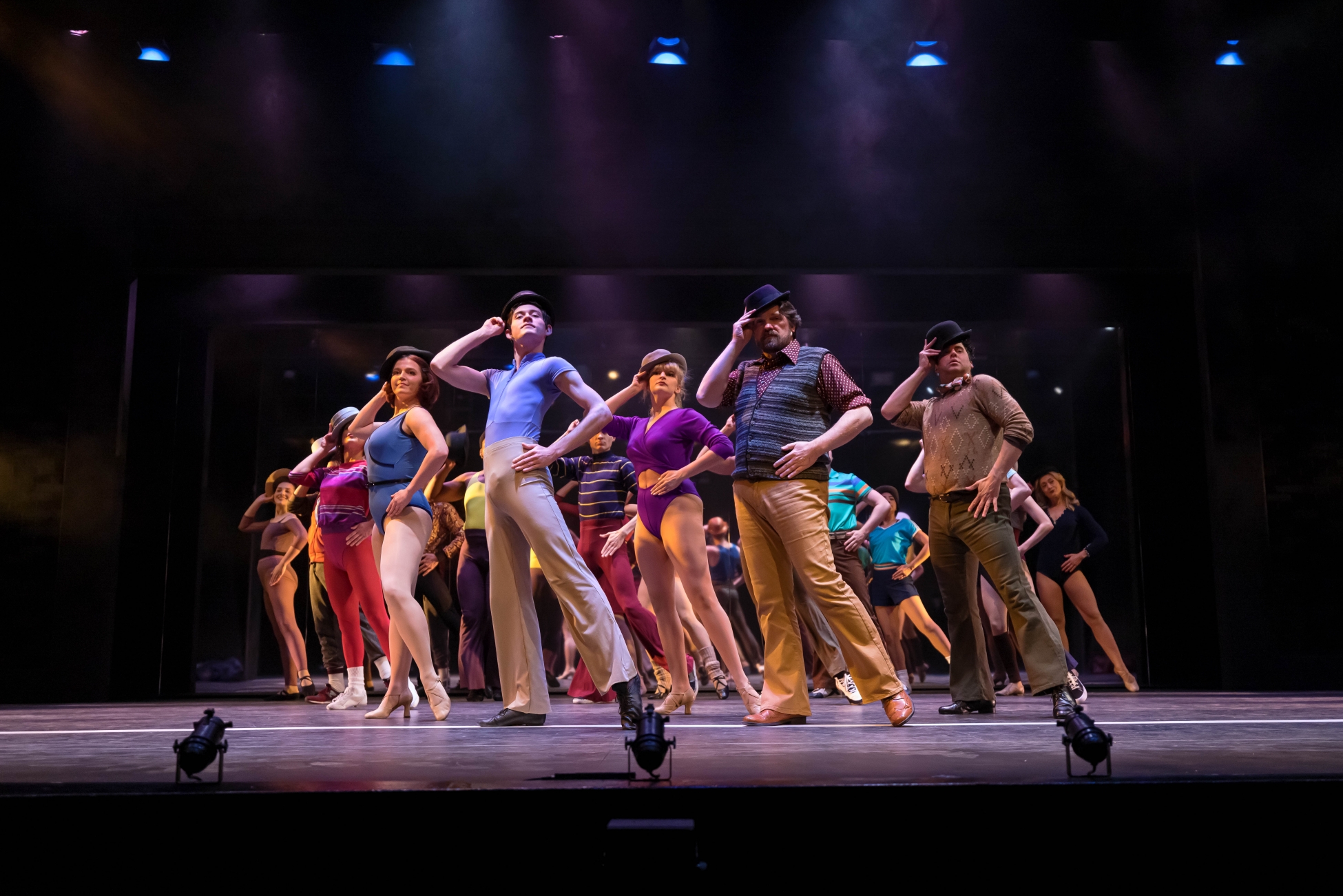 A group of dancers in A Chorus Line pose with hats.