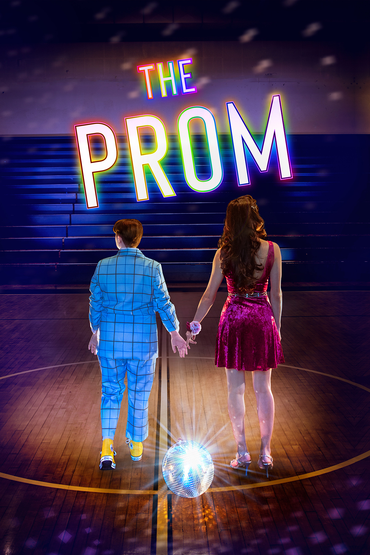A queer couple holds hands, their back turned to the audience in an empty gym near a disco ball. The Prom is in text above them.