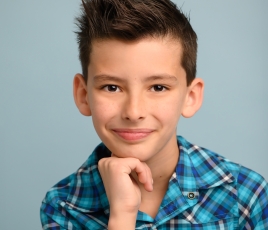 Beckett Beulna is a boy with short brown hair and wears a blue checkered shirt against a blue background.