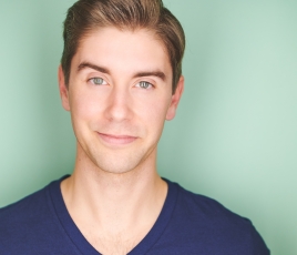 Stephen Hohendorf has short brown hair and wears a dark blue v-neck shirt in front of a green background.