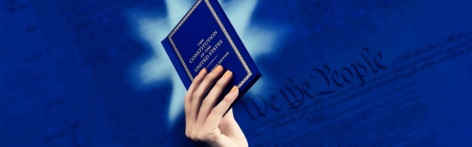 A woman holds a blue pocket sized version of The Constiution of the United States
