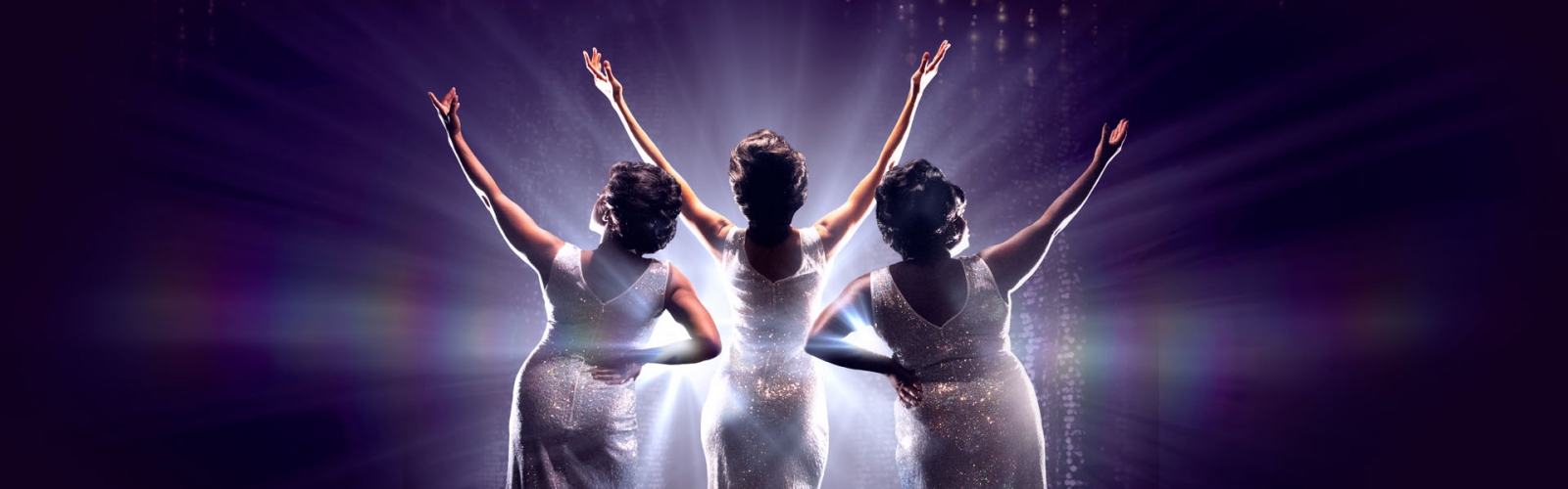 Three women with their arms up in a V in silver sequin gowns