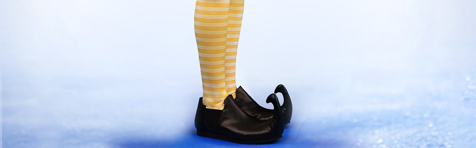A man wears striped yellow tights and pointy brown shoes.